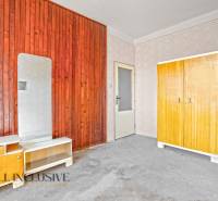 An older interior with wooden paneling, a wardrobe, and a mirror in a family house.