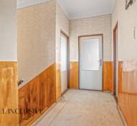 A hallway in a family house with wood paneling and textured walls.