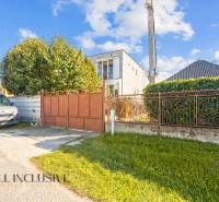 A family house in Veľká Mača with a gate, a car, and greenery in the front yard.