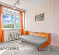 A room in a family house with orange curtains, a sofa, and a painting on the wall.