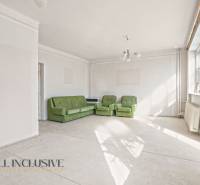 Living room in a family house with three green sofas and large windows.