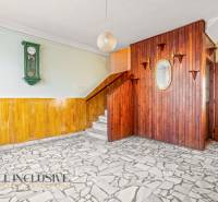 Interior of a family house with wooden paneling, wall clock, and mosaic floor.