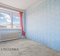 A room in a family house with blue wallpaper and red curtains on the window.