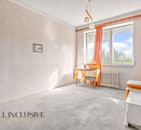 A room in a family house with wallpaper, a desk, and orange curtains.
