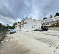 A parking lot in front of the offices in Dubnica nad Váhom surrounded by buildings and parked cars.