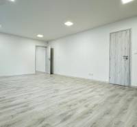 A spacious office with white walls and a floor with a wood decor.
