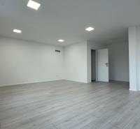 Empty offices with wood-patterned flooring and white walls.