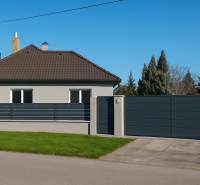 A family house in Horné Saliby with a flat roof, a fence, and a landscaped lawn.