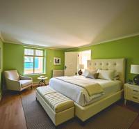 Bedroom with wood-patterned flooring and green walls in a family house.