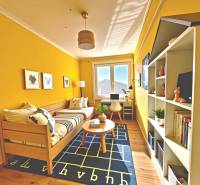 Yellow room with a bed, table, shelves, and a desk in a family house.