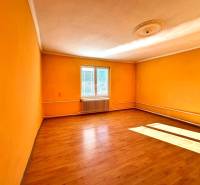 A room in a family house with orange walls and a wood-patterned floor.