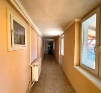 Hallway in a family house with a tiled floor and windows with blinds.