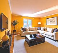 Living room with a sofa, television, tables, and decorations in a family house.