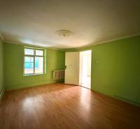 A room in a family house with green walls and a wood-patterned floor.