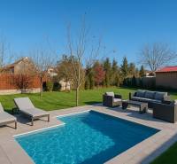 The courtyard of a family house in Horné Saliby with a garden pool and deck chairs.