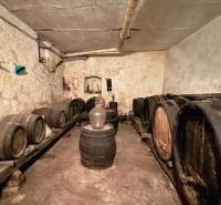 A wine cellar with wooden barrels in the basement of a family house, softly illuminated by the space.