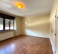 A spacious room in a family house with a wooden decor floor and a large window.