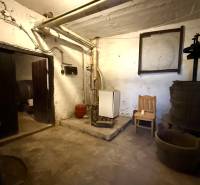 A basement in a family house with a boiler, technical equipment, and a wooden press.