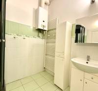 Bathroom in a family house with tiles, a sink, a mirror, and a water heater.