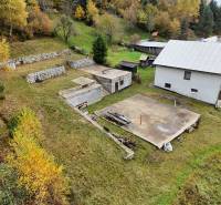 A plot in Bacúch with foundations for construction, surrounded by autumn nature and a nearby house.