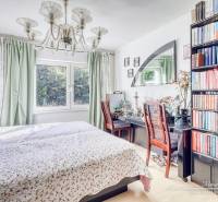 A bedroom in a family house with a bookshelf, chandelier, and large mirror.