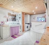 A bathroom in a cottage with white tiles, a bathtub, and accessories in lilac shade.