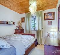 A bedroom in a family house with a wooden ceiling, chandeliers, and decorated walls.