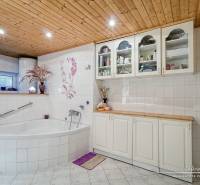 A bathroom in a family house with a corner bathtub and a wooden ceiling, decorated tiles.