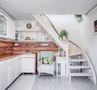 A kitchen in a family house with white furniture and a staircase, equipped with wooden decor.
