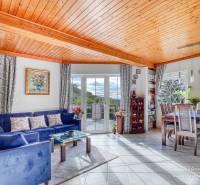 Living room in a cottage with a wooden ceiling, blue sofa, and dining table.