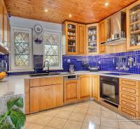 A kitchen in a family house with a wooden ceiling, blue tiles, and a wooden decor kitchen unit.