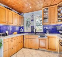 A kitchen in a cottage with wooden decor, blue tiles, and appliances.