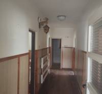 A hallway in a family house with a wooden decor floor and wooden wall paneling.