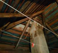 Rafters and walls in the attic of a family house, view of wooden beams and chimney.
