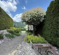 The exterior of the villa in Súľov-Hradná with a pathway, greenery, and a wooden cart.