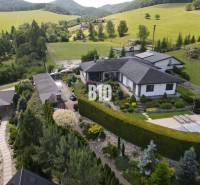 A villa in Súľov-Hradná surrounded by a beautiful garden and hilly landscape.