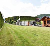 A well-maintained lawn at a villa in Súľov-Hradná with a wooden house and a hedge.