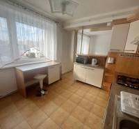 A kitchen in a 3-room apartment with a tiled floor and furniture with a wooden decor.