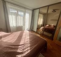 A bedroom in a 3-room apartment with a wooden decor floor and a mirrored wardrobe.