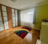 A room in a 3-room apartment with a wooden decor floor and a colorful carpet.