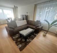 Living room with a sofa, table, and wood-patterned floor in a 3-room apartment.