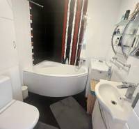A bathroom in a 3-room apartment with a bathtub, black tiles, and a washing machine.