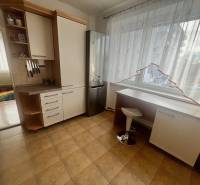 A kitchen in a 3-room apartment with tiles, white furniture, and a large window.
