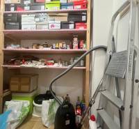 A warehouse with shelves, boxes, a vacuum cleaner, and a ladder in a 3-room apartment.