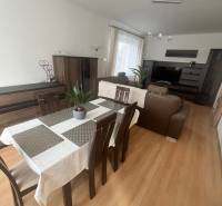 Dining room in a 3-room apartment with a sofa, wood-patterned flooring, and a television.