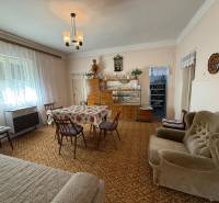 Living room in a family house with carpeted floor, floral tablecloth, and retro furniture.