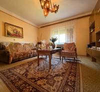 Living room in a family house with a carpet, sofa, chair, and chandelier.