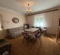 Living room in a family house with a carpet, sofa, and dining table with chairs.