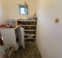 A pantry in a family house with a freezer, a shelf for preserves, and a small window.