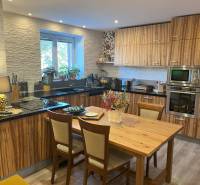 A kitchen in a 2-room apartment with built-in appliances and wooden furniture.